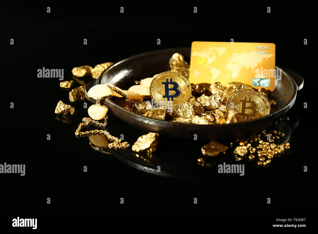 Tray with gold nuggets, bitcoins, credit card and necklace on black ...