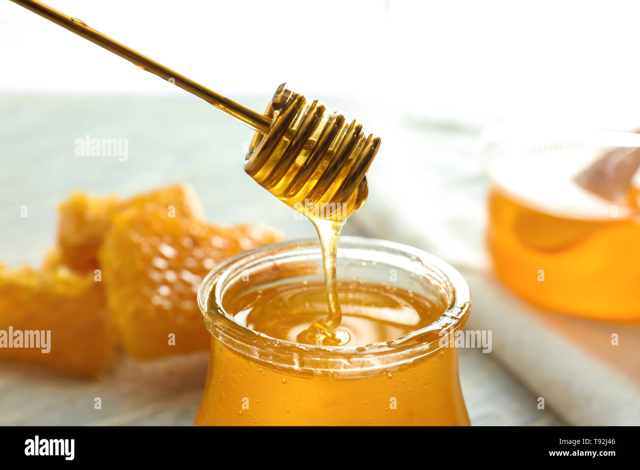 Honey dripping from dipper into glass jar, closeup Stock Photo - Alamy