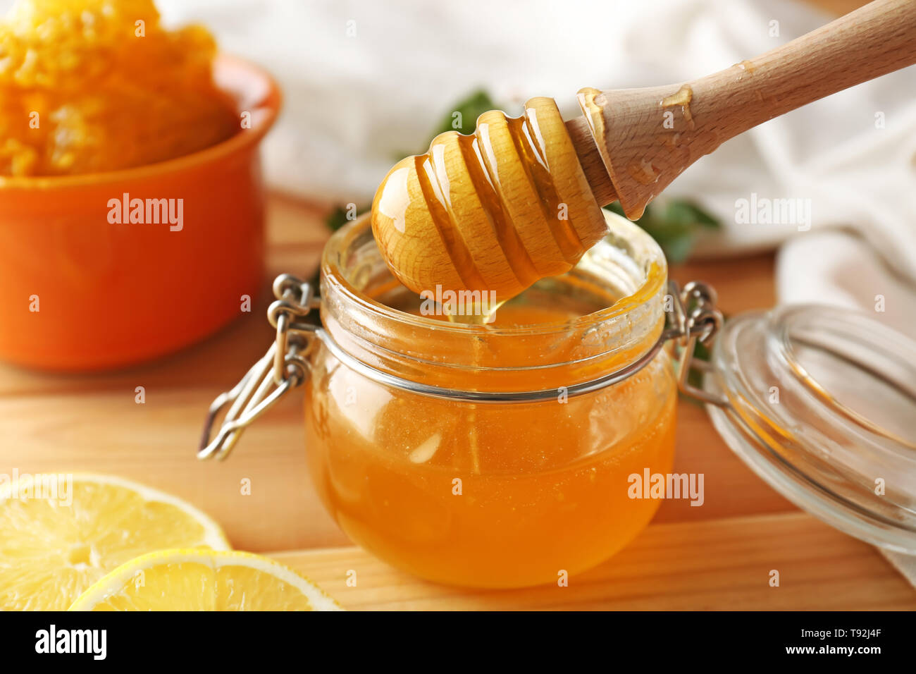 Honey dripping from dipper into jar on table, closeup Stock Photo - Alamy