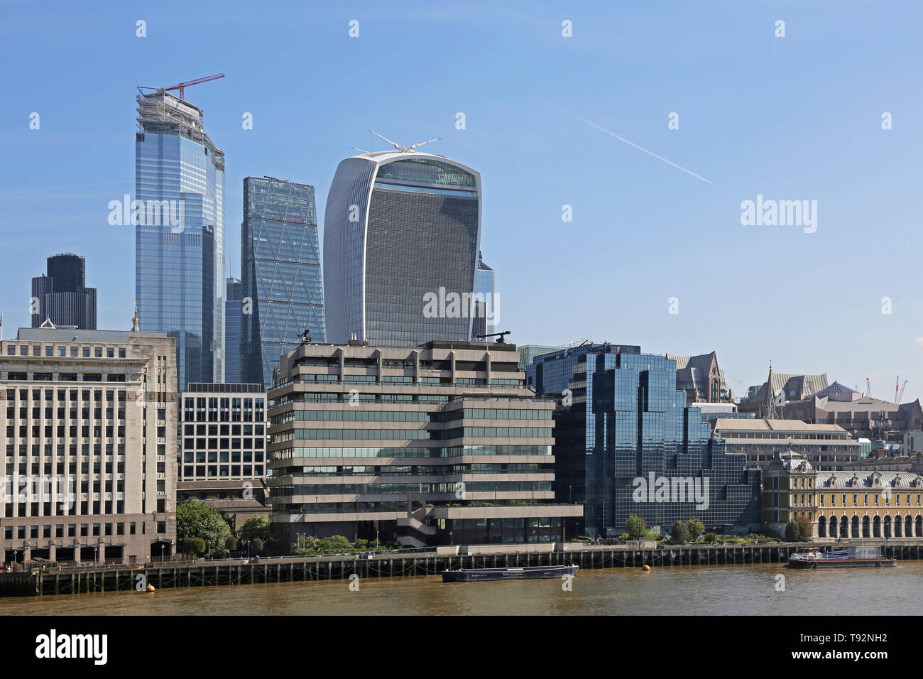 London City skyline - summer 2019. Shows The Pinnacle (under construction), the Cheese-grater and Walkie-Talkie building. River Thames in foreground. Stock Photo