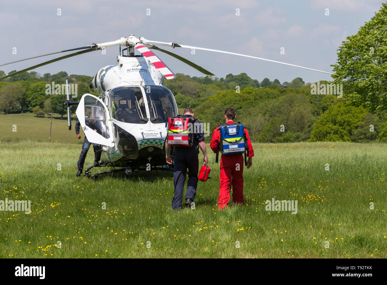 Air ambulance crew walk towards a kent surrey sussex MD902 Explorer helicopter after a callout in tenterden, kent, uk Stock Photo
