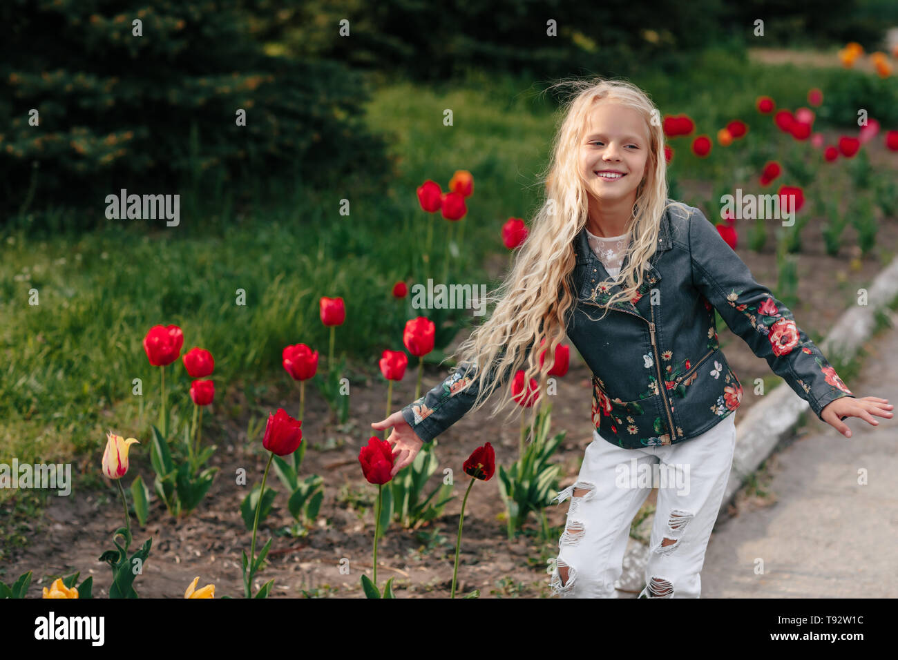 portrait of a beautiful little child girl with tulip flowers on a sunny spring day Stock Photo
