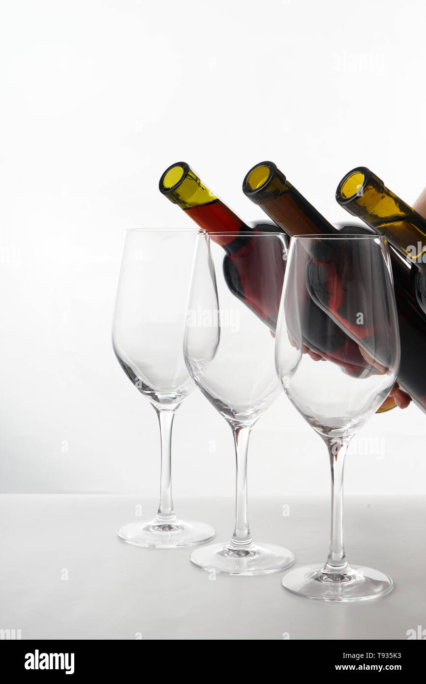 Pouring of different wine from bottles into glasses on white background