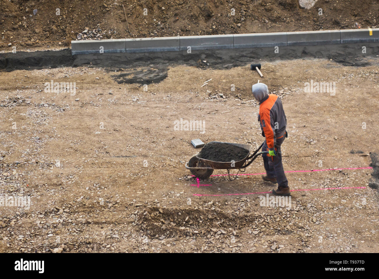 laborer carrying a wheelbarrow at a construction site Stock Photo