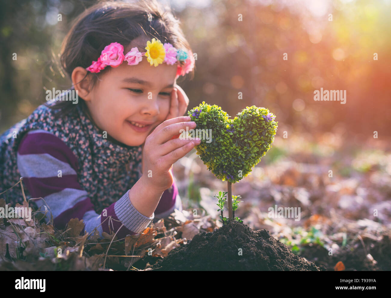 Beautiful little girl planting a heartshaped tree and dreaming of a