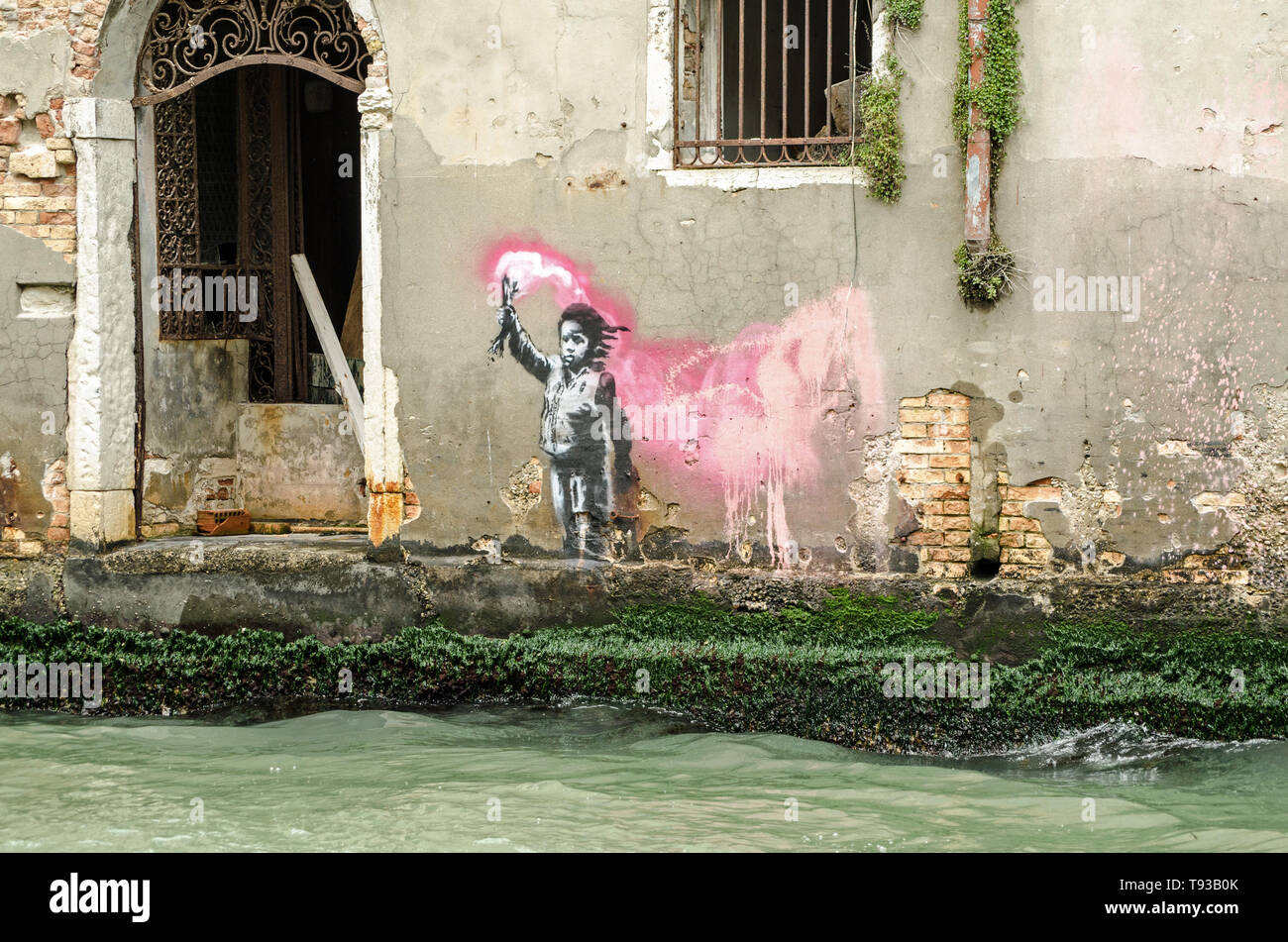 VENICE, ITALY - MAY 15, 2019:  Stencil street art of a child wearing a lifejacket and waving a flare attributed to graffiti artist Banksy.  Viewed fro Stock Photo