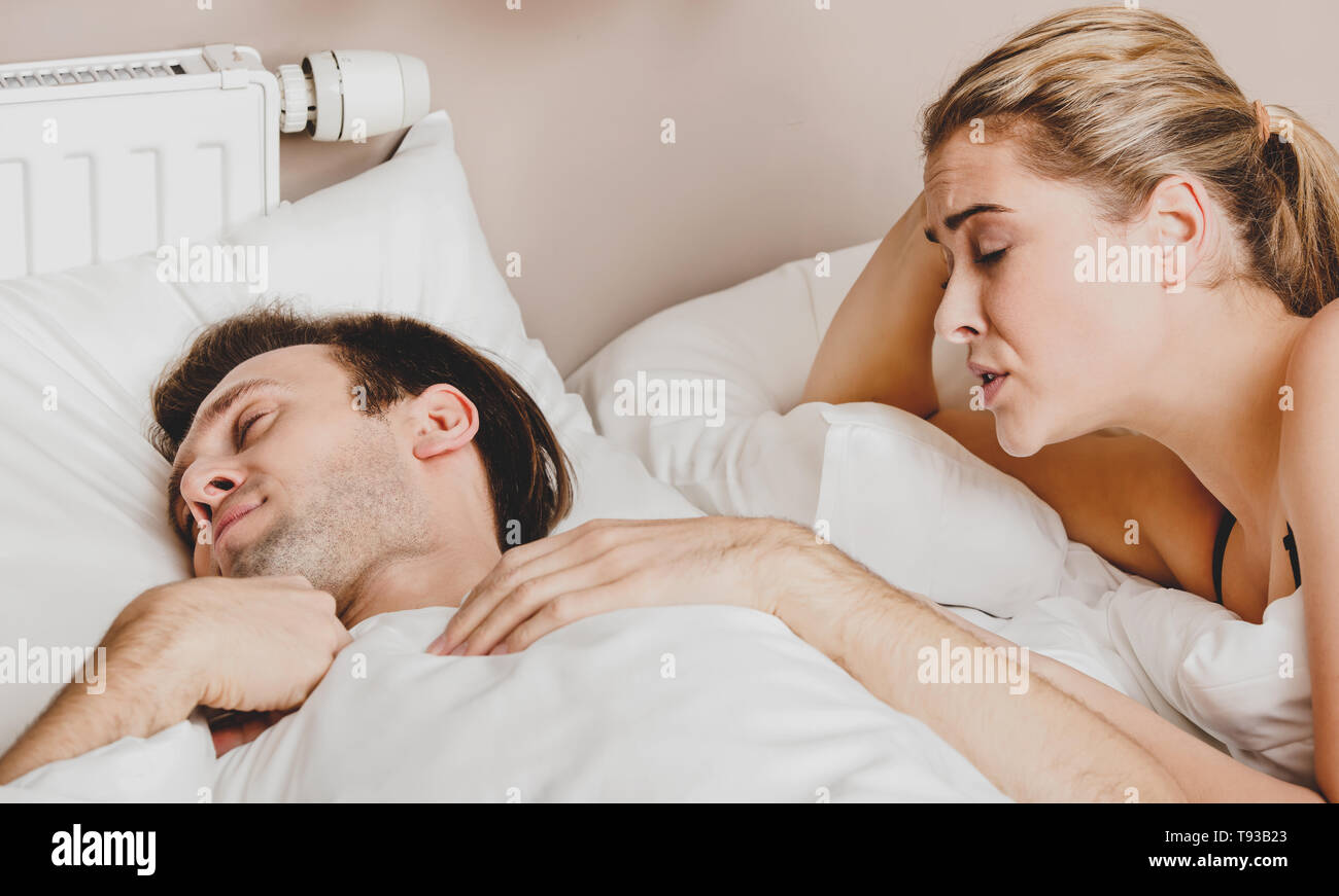 Copule in bed. Woman trying to wake him, in morning. They are waking up. Stock Photo