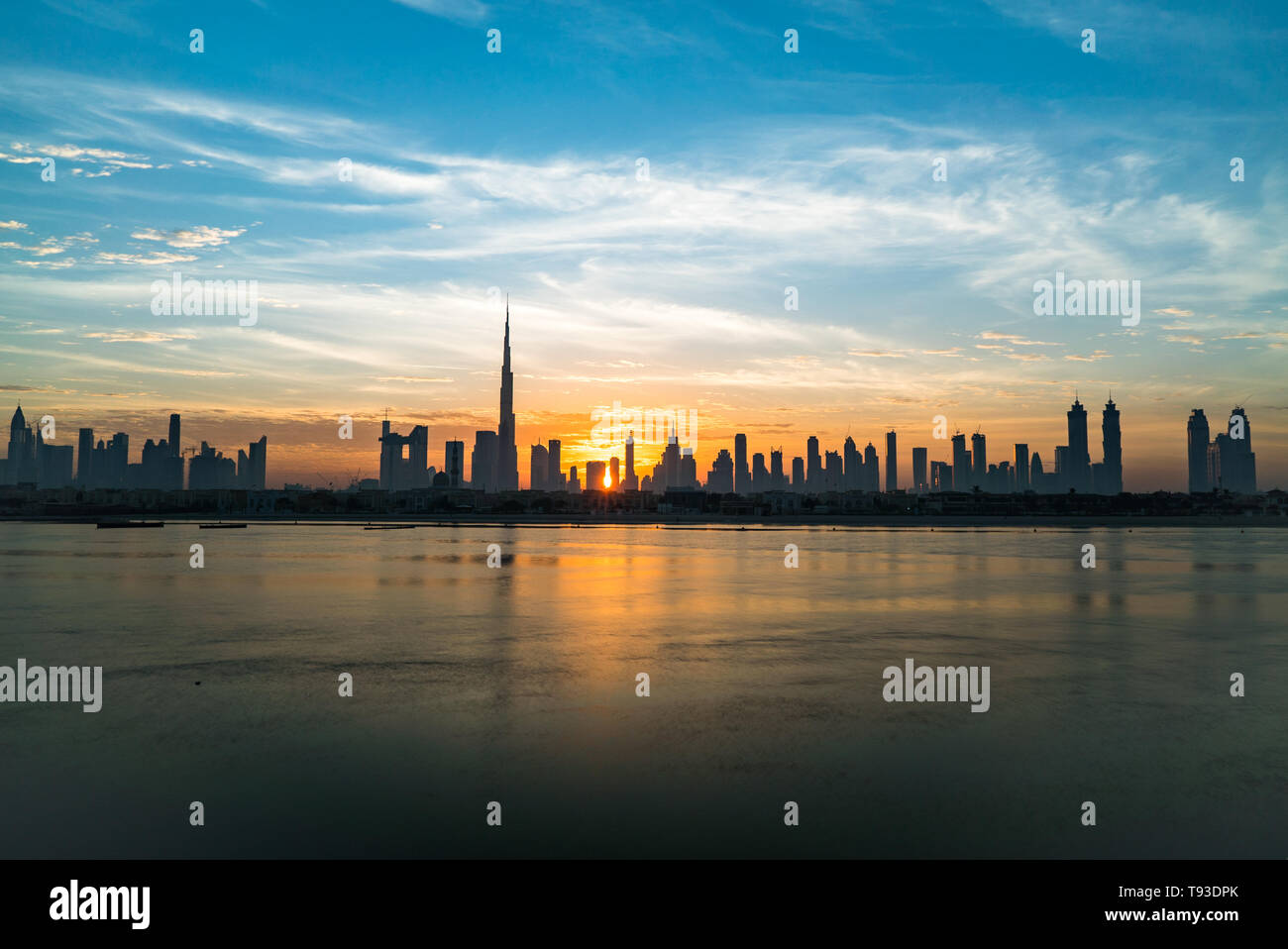 Morning or sunrise, dawn in Dubai. Beautiful colored cloudy sky over downtown Dubai. Solar path on sea. Stock Photo