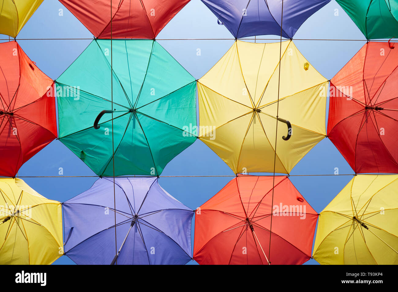 Background of multicolored umbrellas hanging against the blue sky. Stock Photo