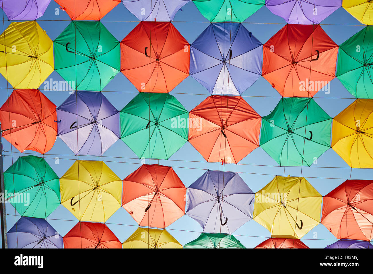Background of multicolored umbrellas hanging against the blue sky. Stock Photo