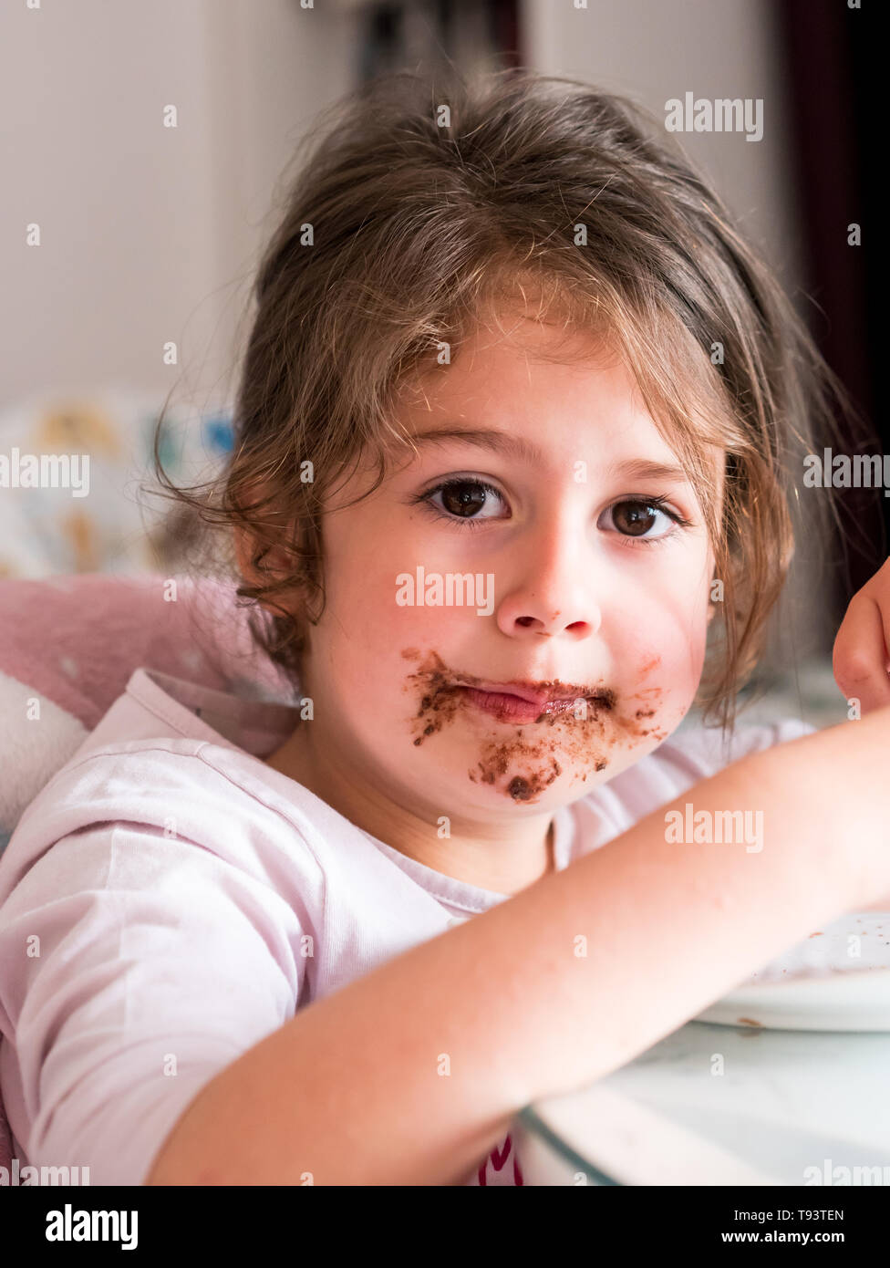 Caucasian girl with chocolate messy face indoors Stock Photo