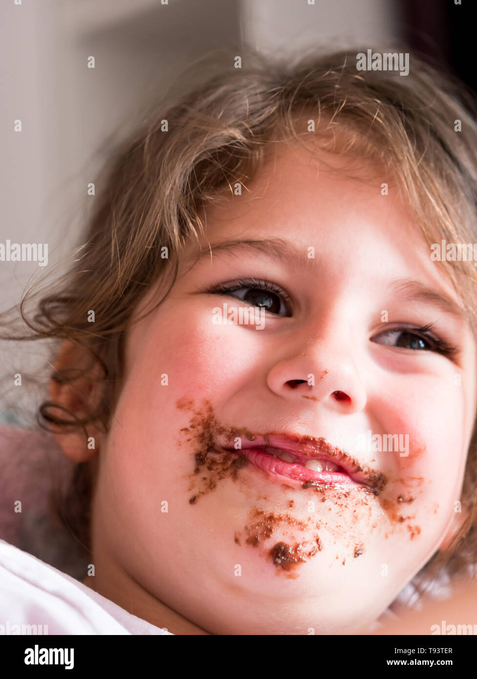 Cute messy with chocolate caucasian girl smiling Stock Photo