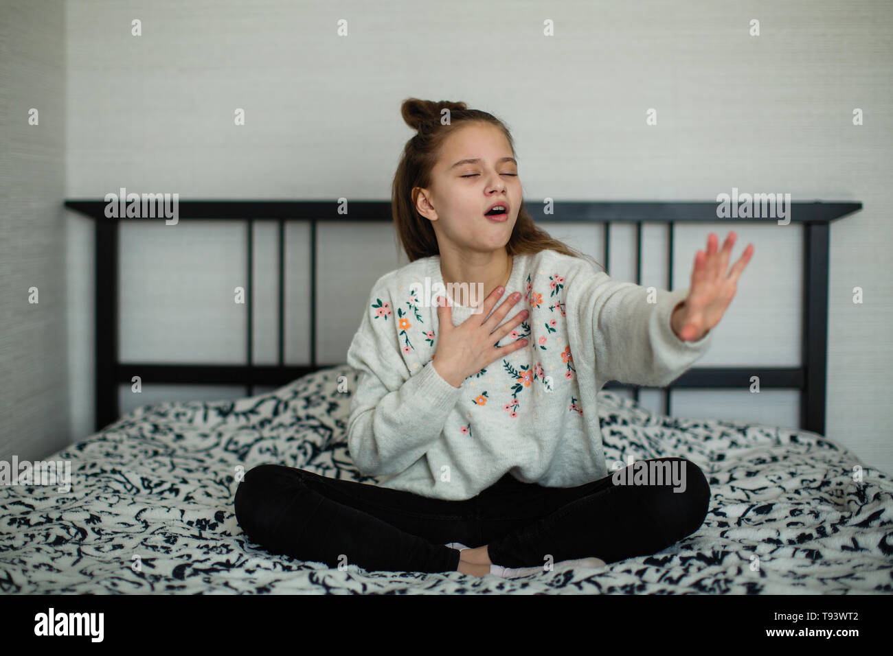 Twelve year old cute girl having fun in her room sitting on the bed