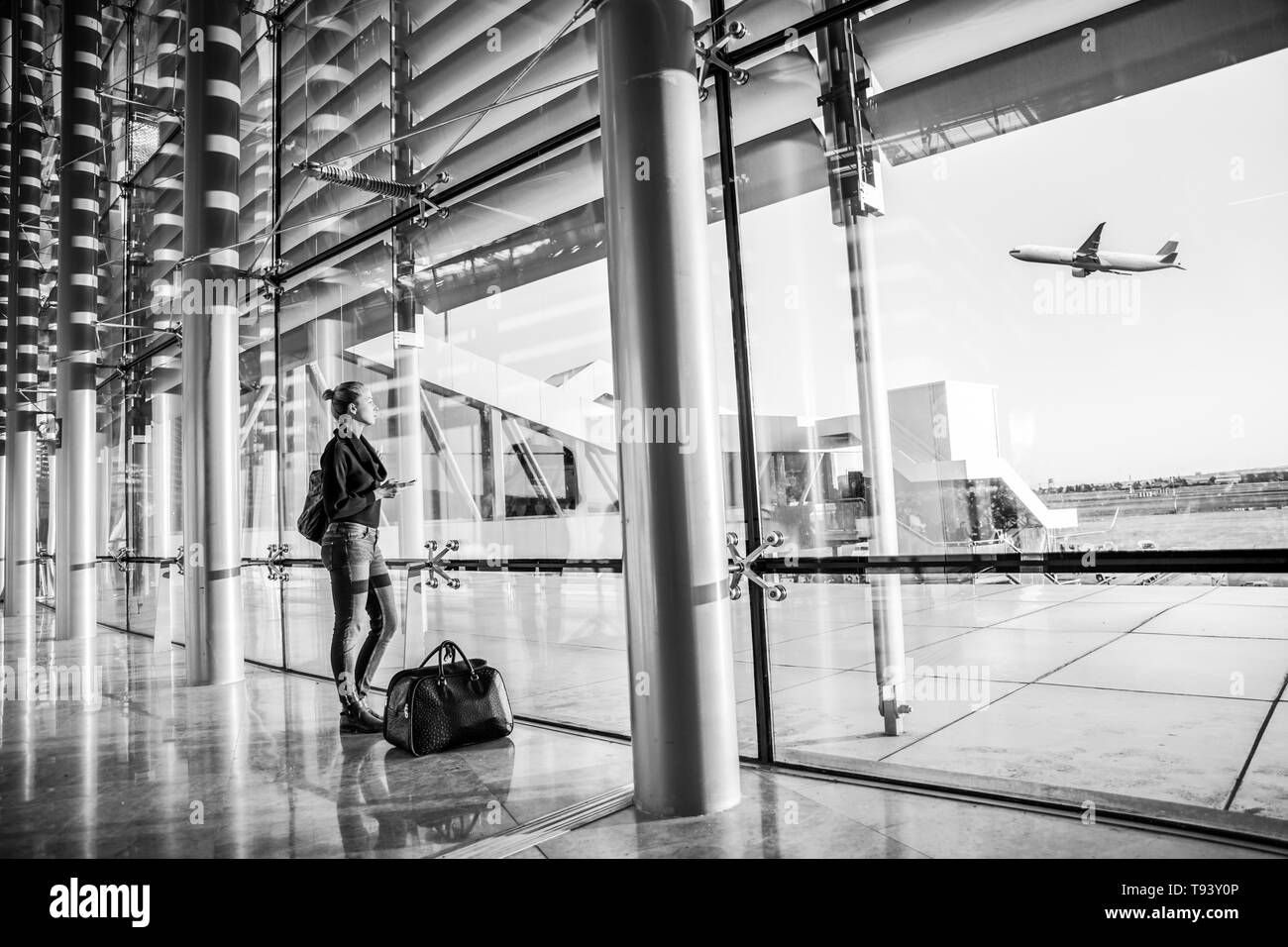 Young woman waiting at airport, looking through the gate window. Stock Photo