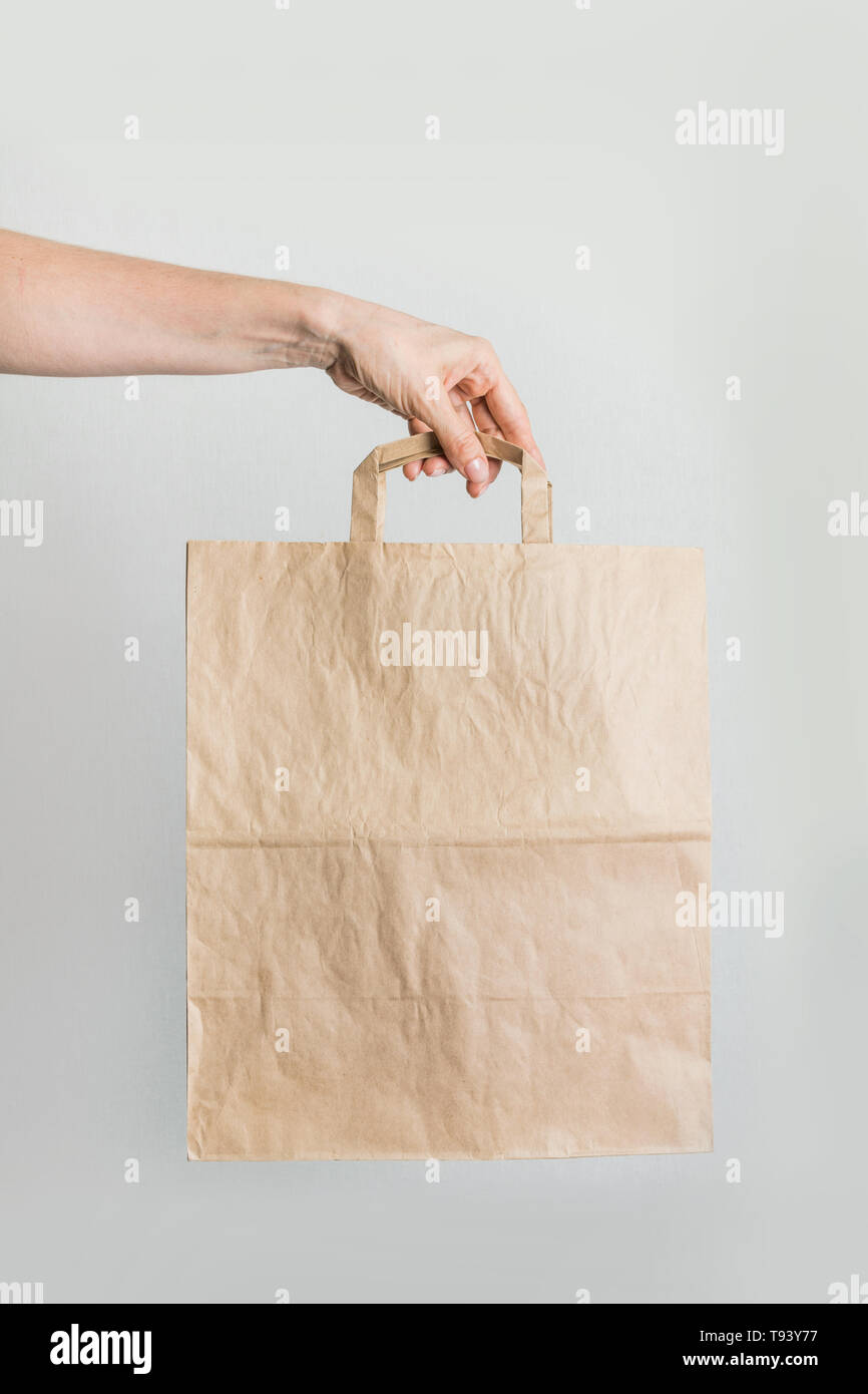 Paper shopping bag in women's hand. Vertical shot. Zero waste concept