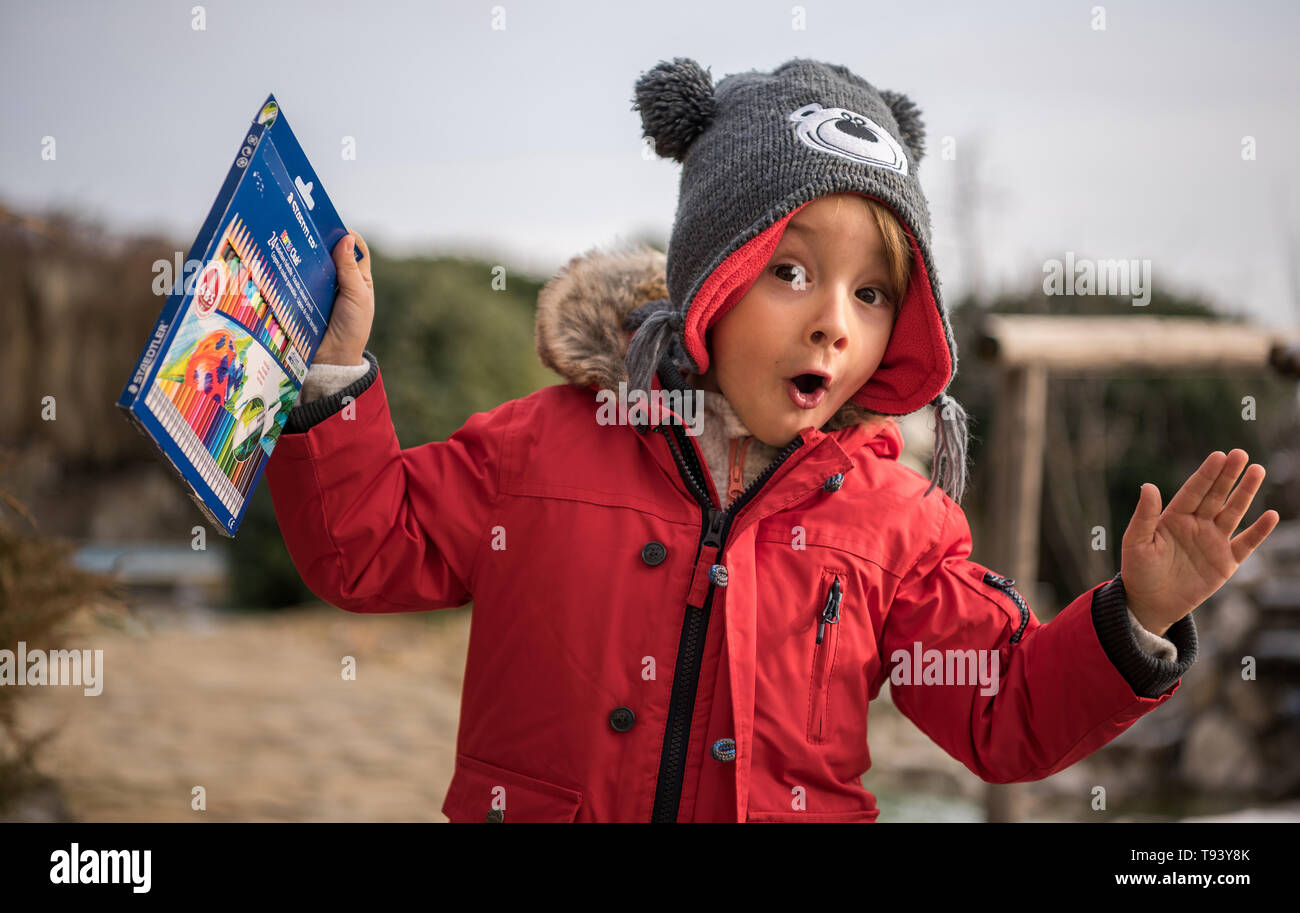 The joy of a child in front of a gift. Very overwhelmed by the fact that he received a new box of colored pencils. Stock Photo