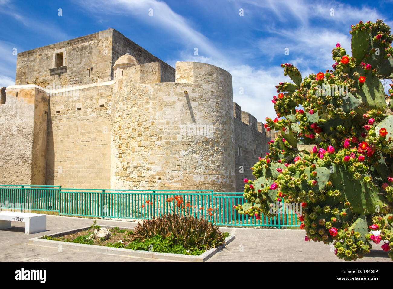 Brucoli Sicily view of old fortress near the sea with plants and flowers in the square in a sunny day Stock Photo