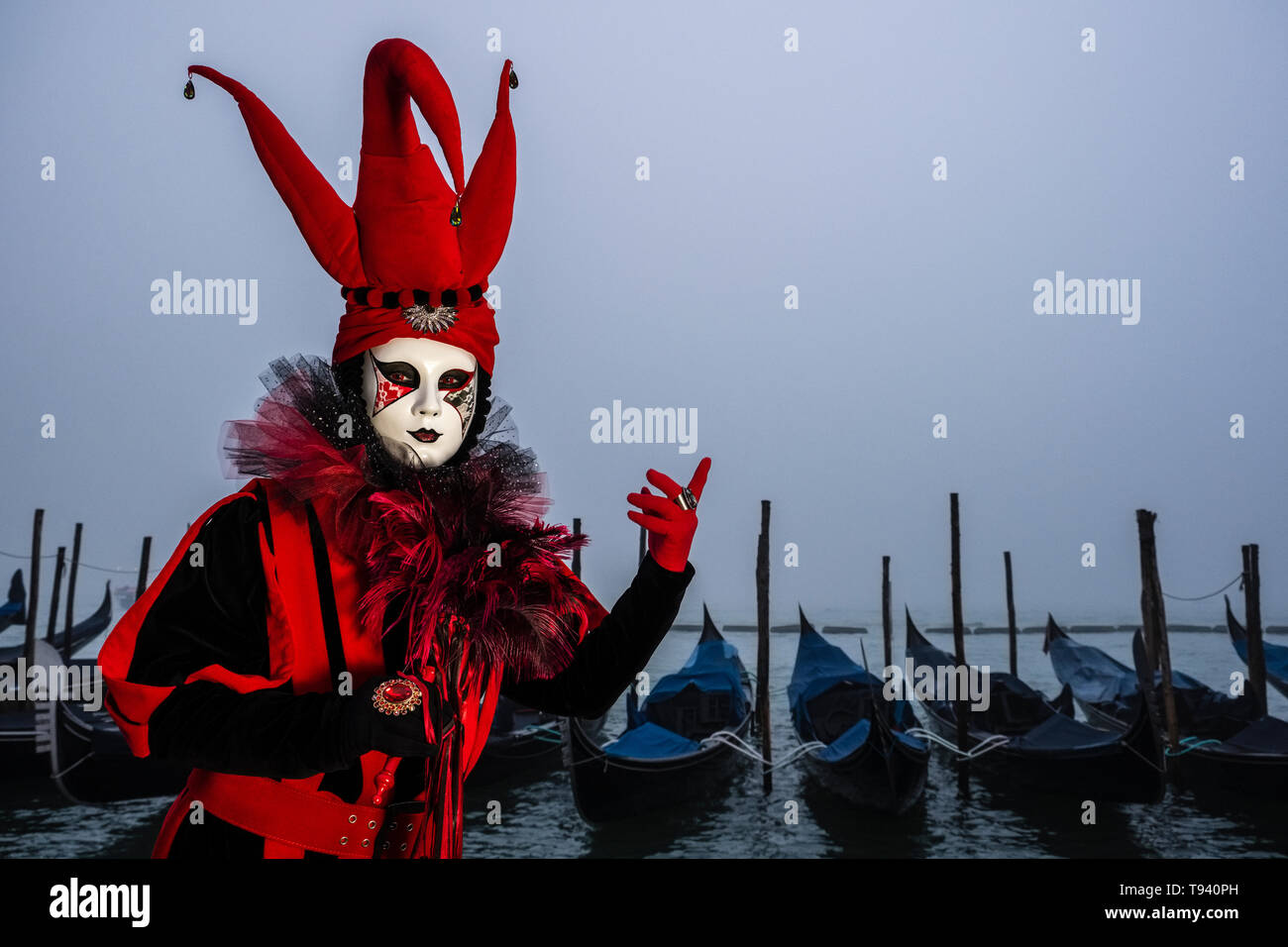 Portrait of a feminin masked person in a beautiful creative harlequin costume, posing at Grand Canal, Canal Grande, celebrating the Venetian Carnival Stock Photo