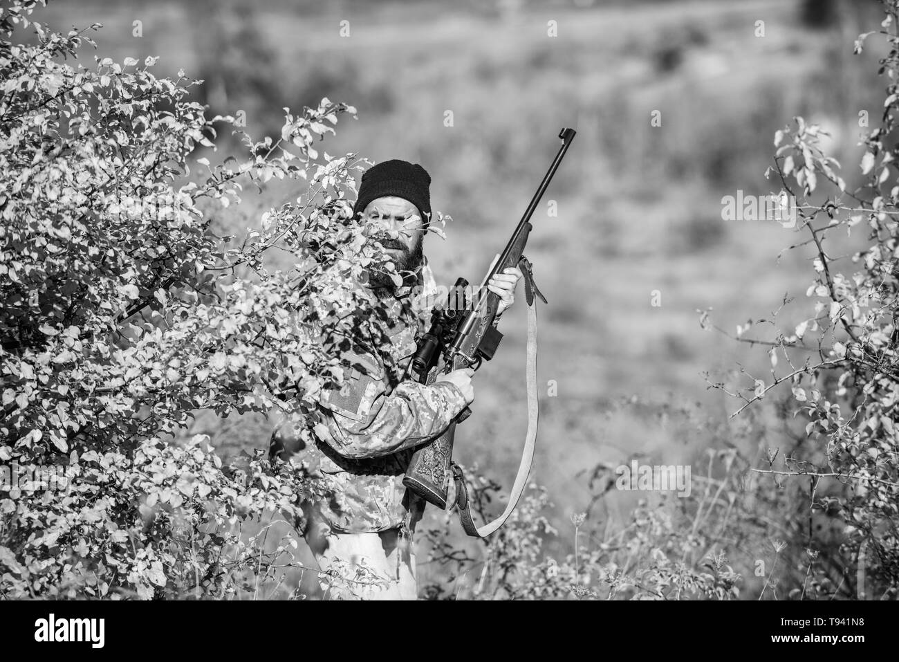 Bearded man hunter. Military uniform fashion. Army forces. Camouflage. Hunting skills and weapon equipment. How turn hunting into hobby. Man hunter with rifle gun. Shoot straight and look great. Stock Photo