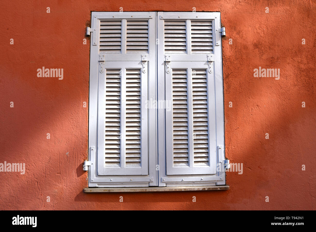 Window closed with white wooden shutters. on a red wall Stock Photo - Alamy