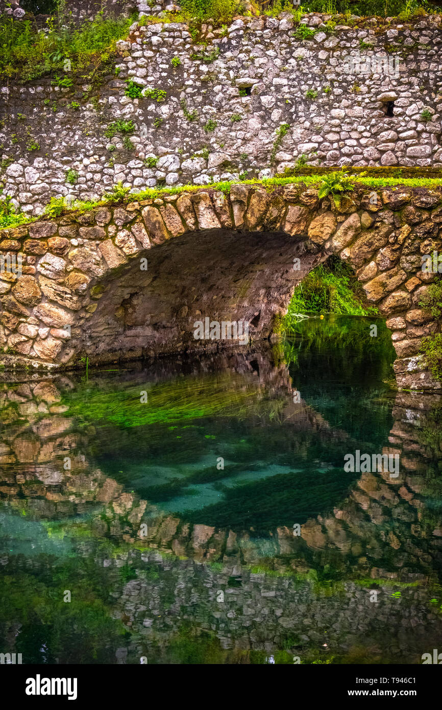 round stone bridge reflected in river water vertical background Stock Photo