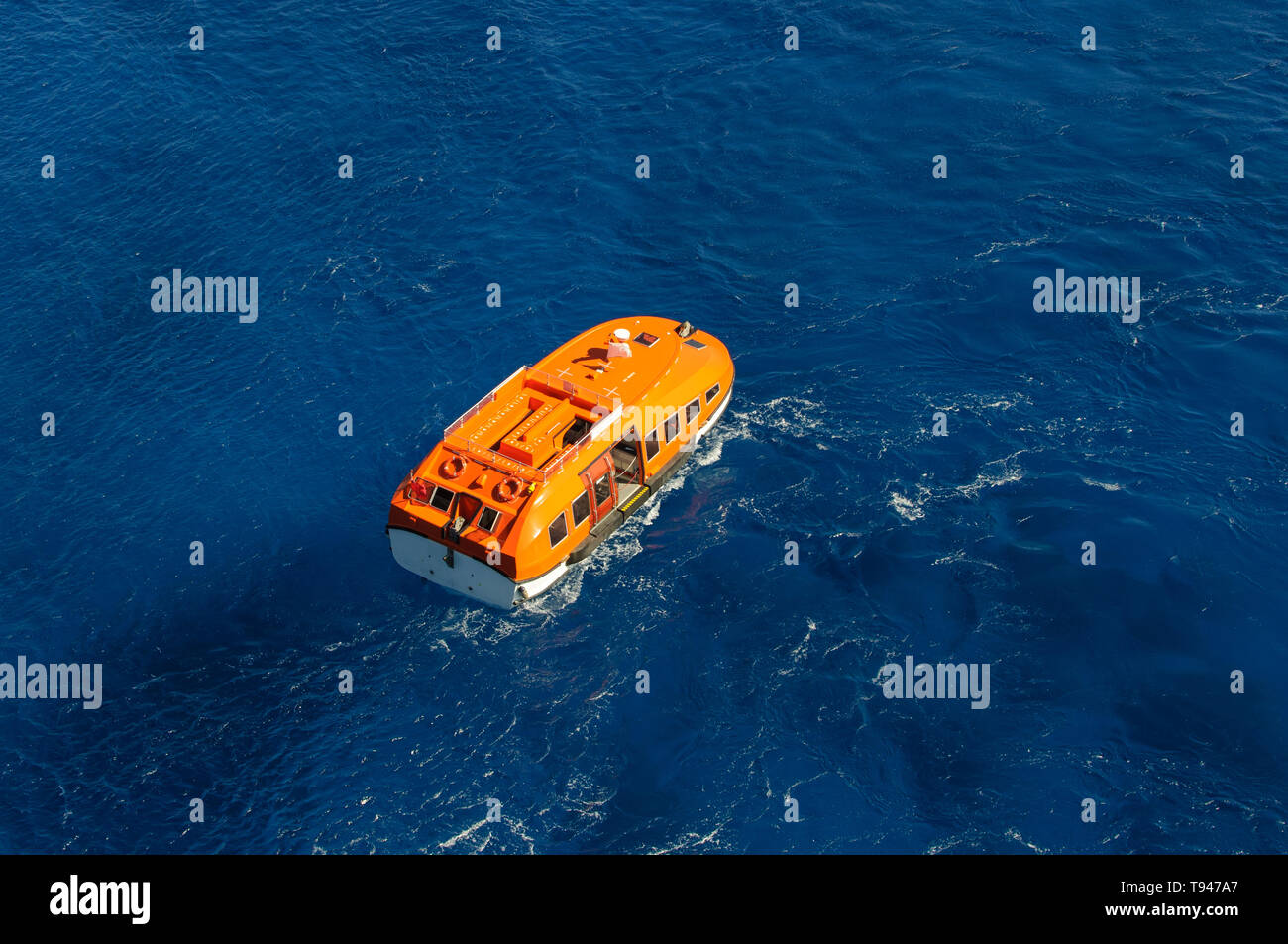 Orange rescue boat on blue sea waves background. Aerial view Stock Photo
