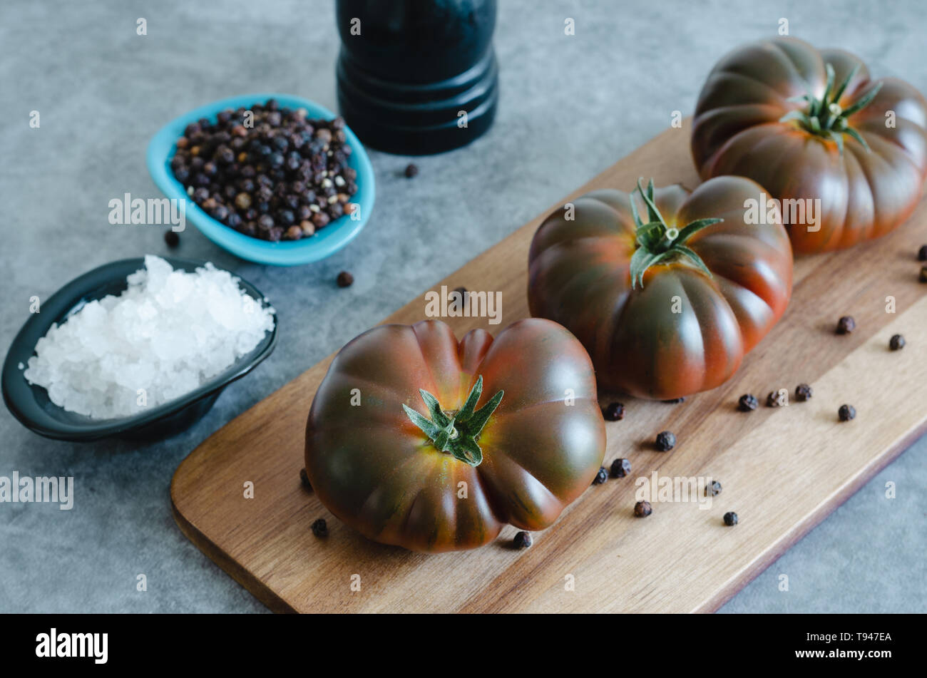 Sweet Marmande tomatoes whole on wooden board. Close view Stock Photo