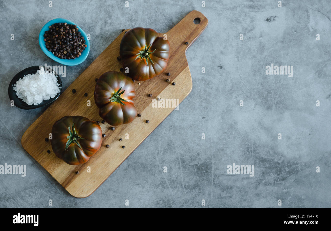 Sweet Marmande tomatoes whole on wooden board. Copy space. Stock Photo