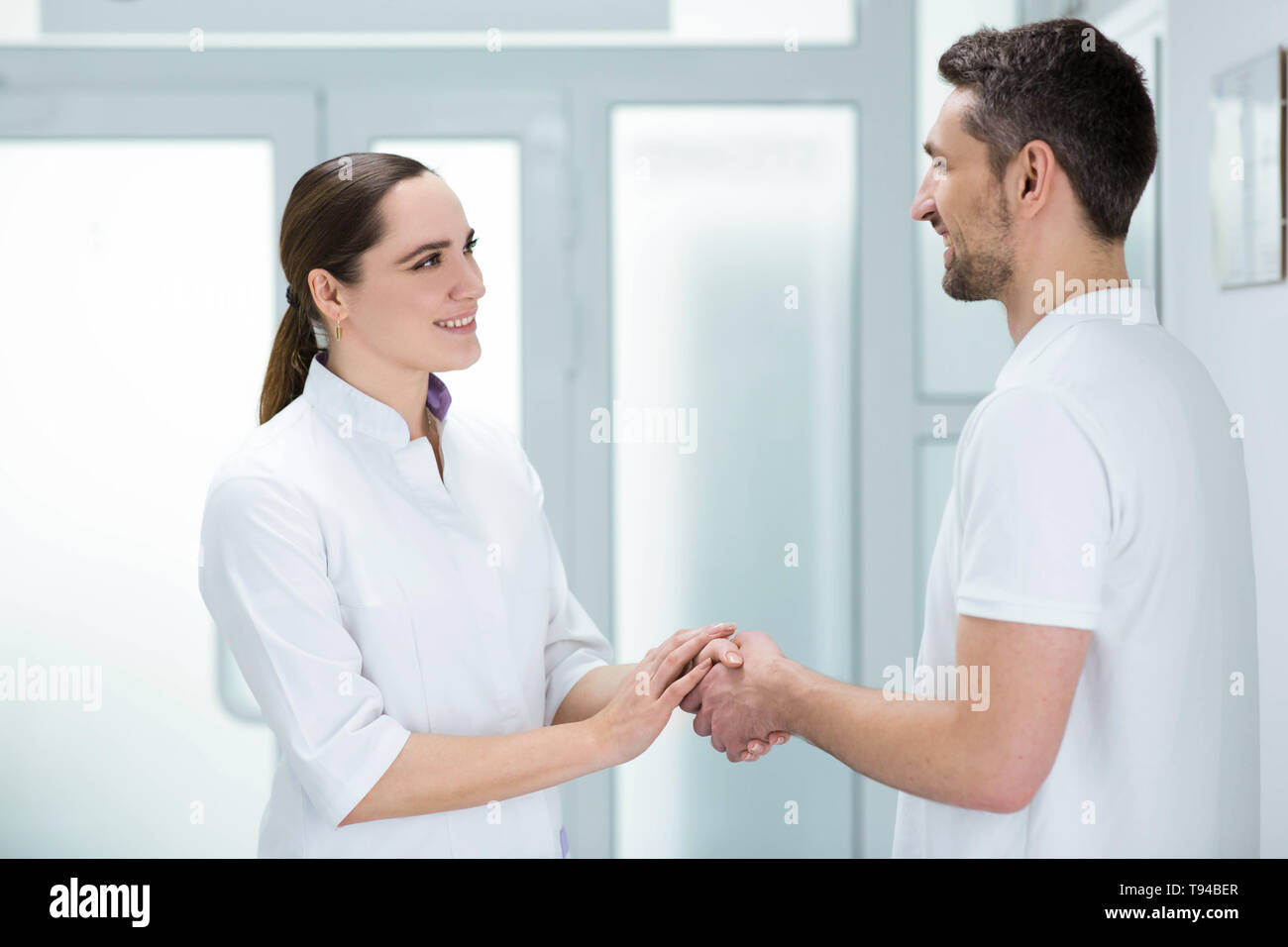 Mid aged doctor getting comfort to her patient at hospital corridor. Stock Photo