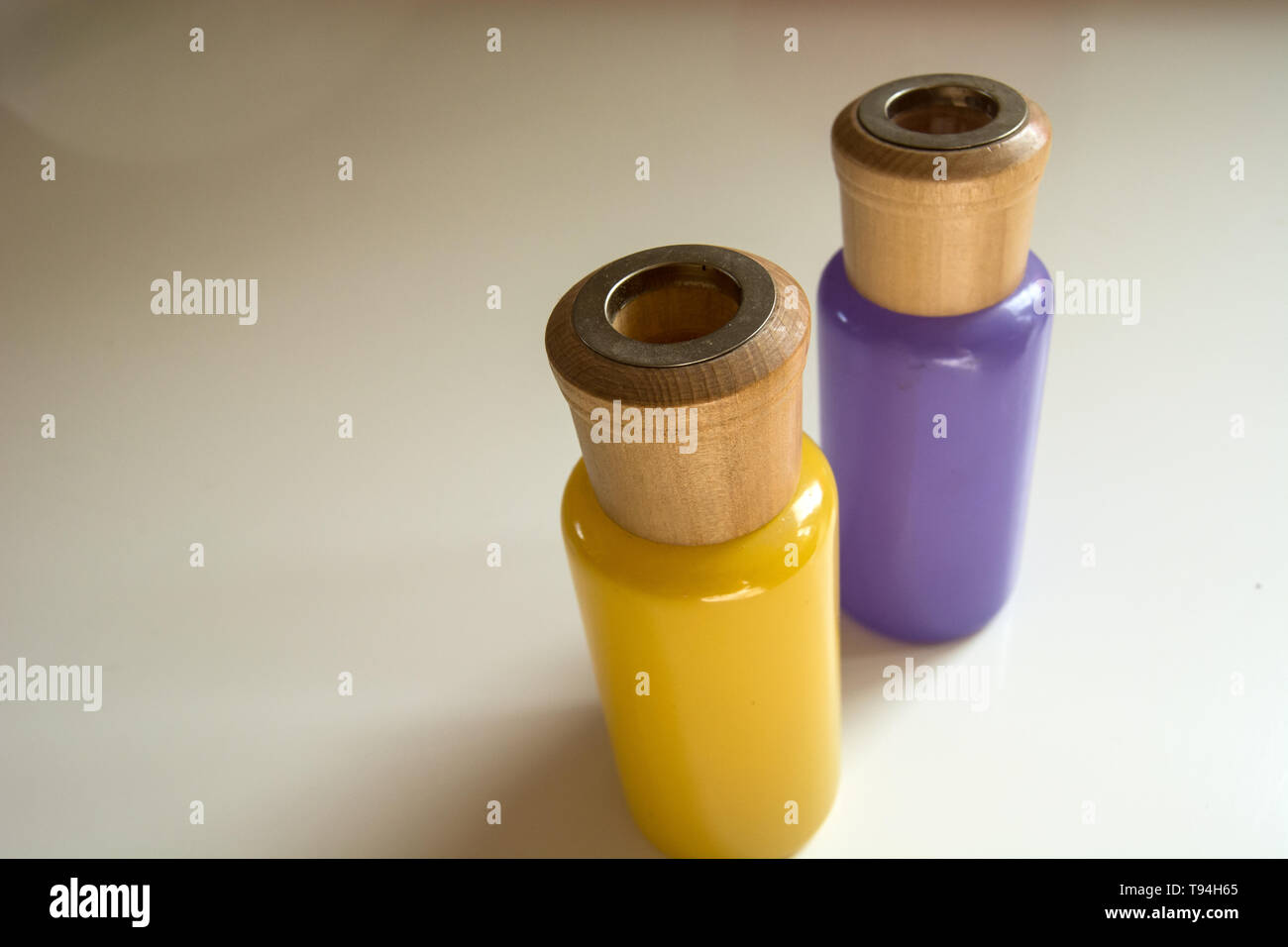 Two glass colored bottles with wooden elements standing on a light background Stock Photo