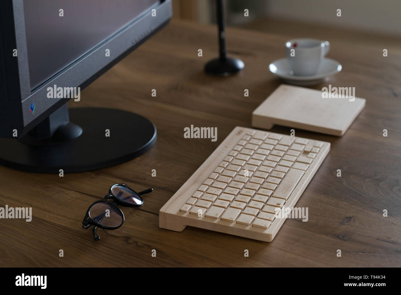 Modena, Italy, 04/07/2018 : Office table desk. Workspace with large black  monitor screen, a wooden keyboard, a trackpad, a graphic pen, glasses, a  cof Stock Photo - Alamy