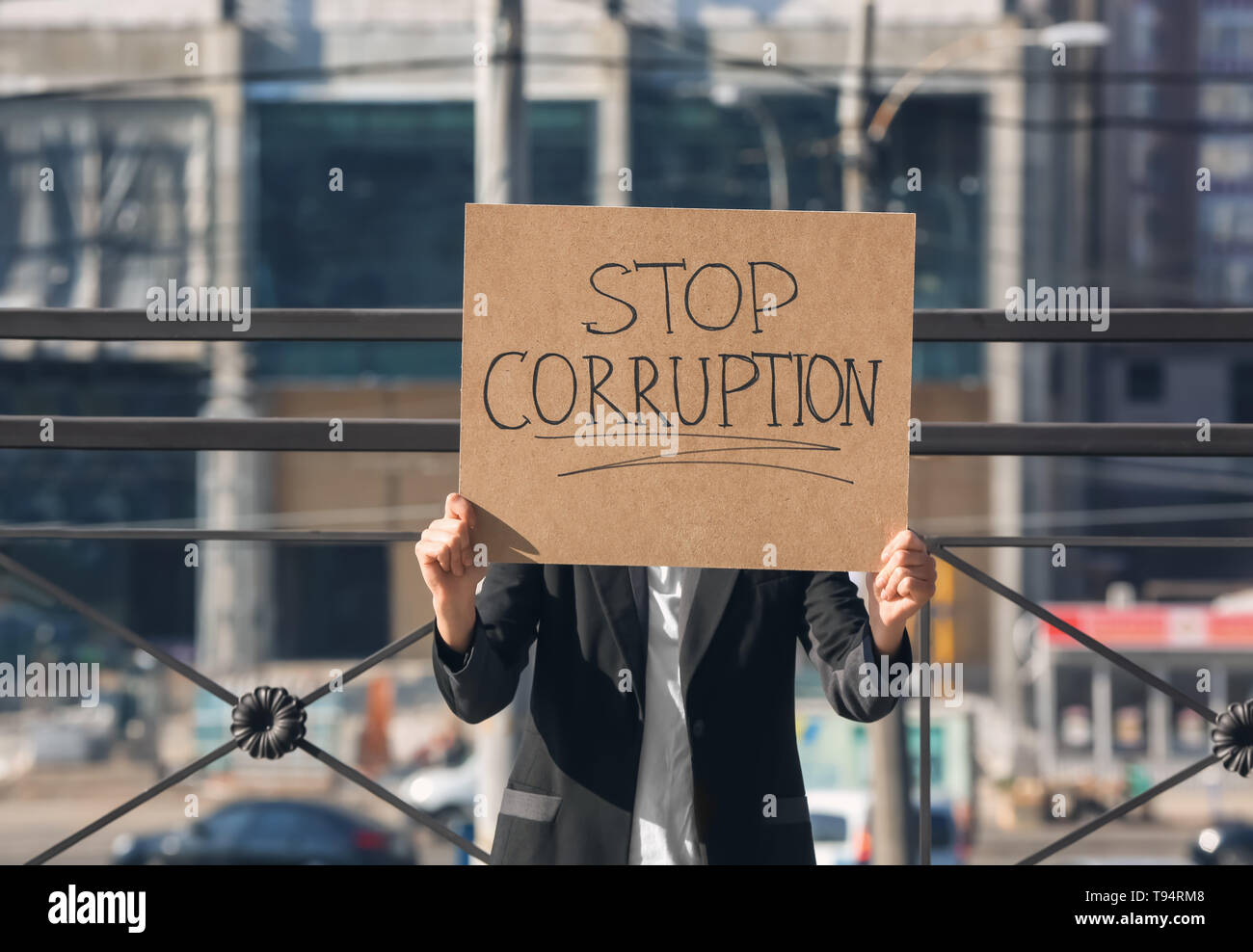 Woman holding placard with text STOP CORRUPTION outdoors Stock Photo