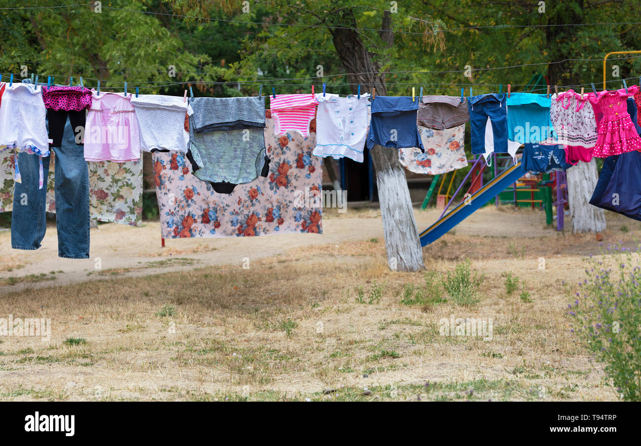 Washing clothes hang on the rope and dry outside over the faded grass in  the courtyard of the street Stock Photo - Alamy