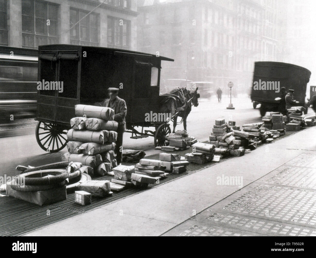 Early parcel post light wagons were standard in length (6' 6'), height (6' 4') and look (green with red running boards, black striping and gold lettering). Among the cargo being loaded in this 1914 photograph are several automobile tires. Parcel post is a postal service for mail that is too heavy for normal letter post. It is usually slower than letter post. Stock Photo