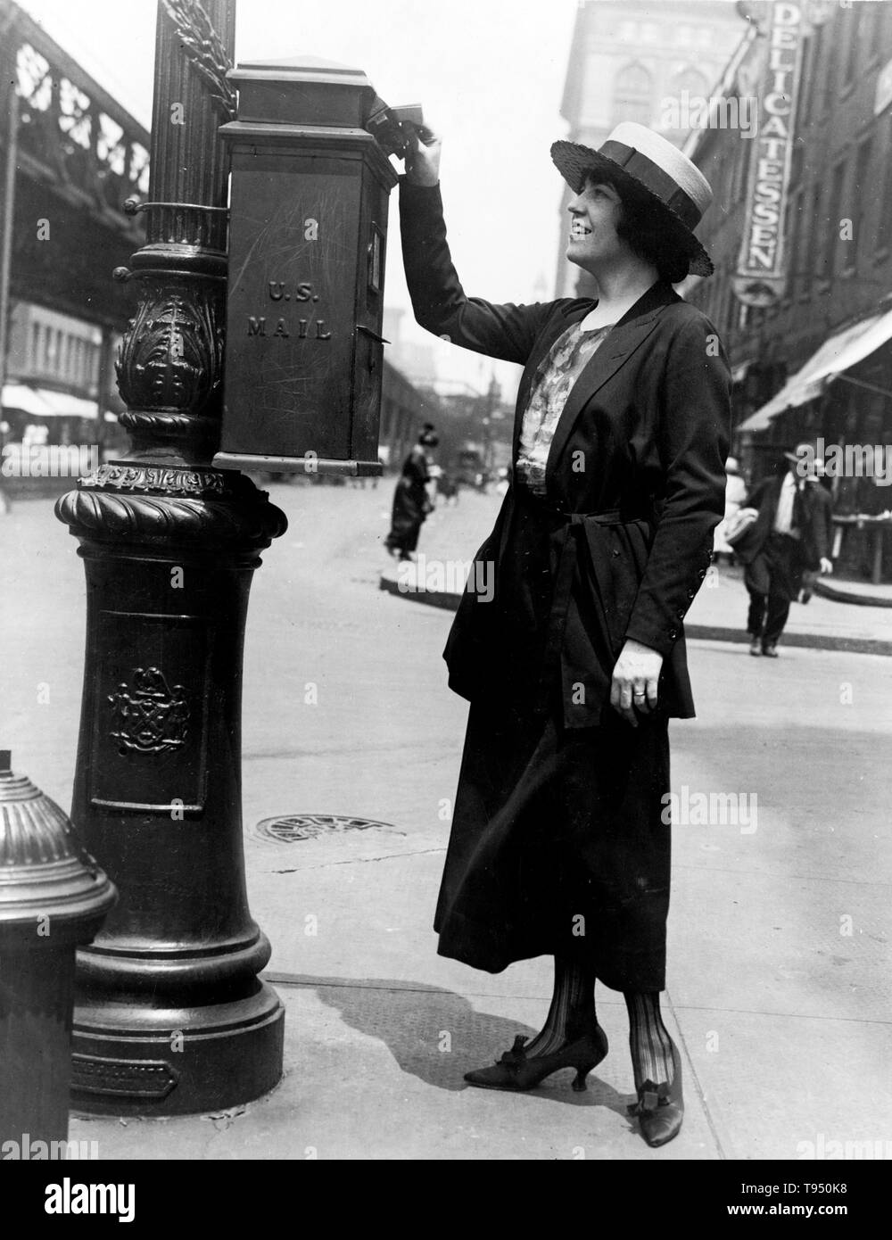 Entitled: 'Merle Alcock (Metropolitan Opera contralto) mailing a letter in New York City' shows a woman putting a letter in a U.S. Mailbox attached to a post on a street corner. A post box, also known as a collection box, mailbox, letter box or drop box is a physical box into which members of the public can deposit outgoing mail intended for collection by the agents of a country's postal service. Stock Photo