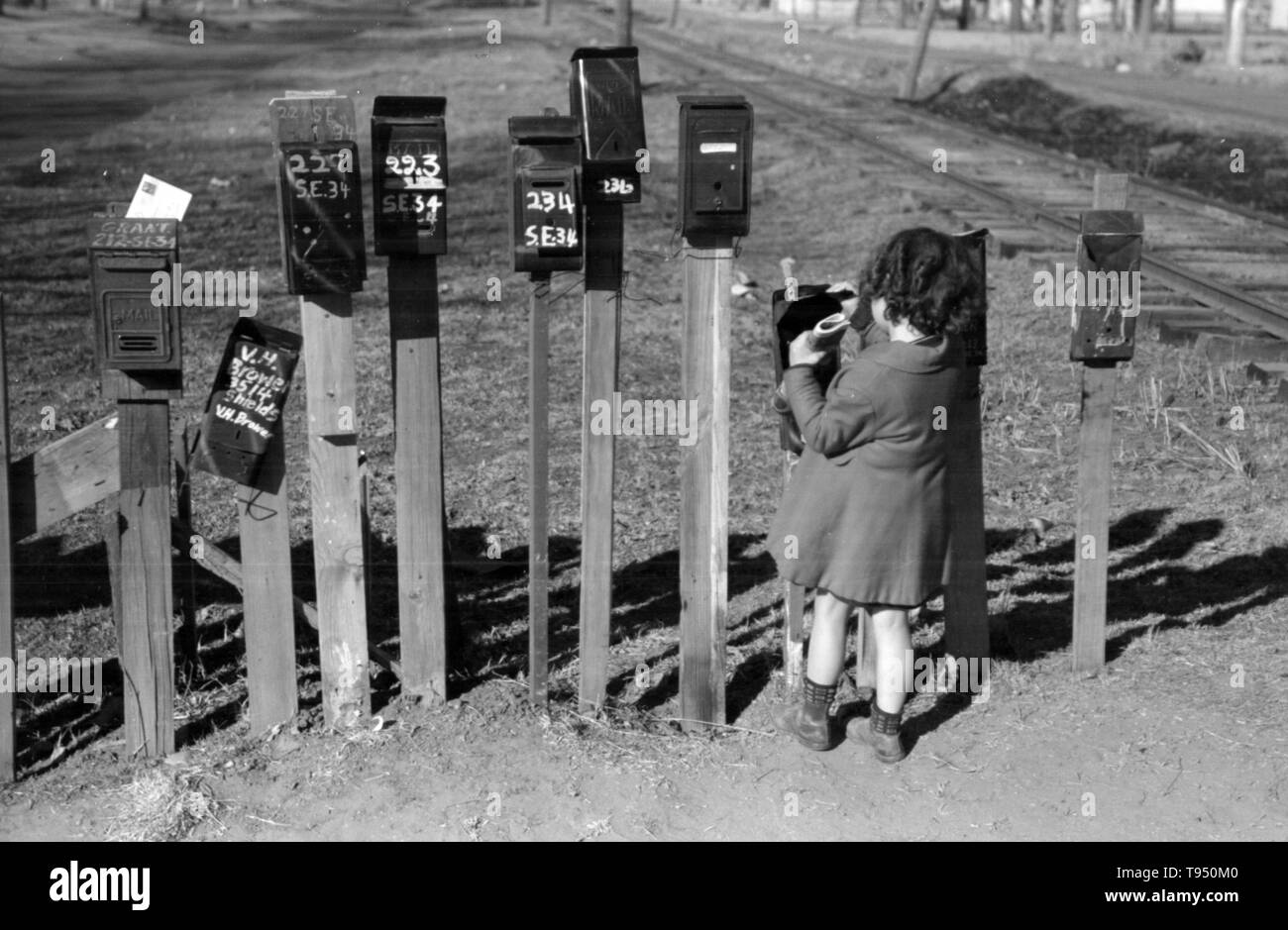 Entitled: 'Little girl getting the mail from box, suburb of Oklahoma City, Oklahoma.' Before the introduction of rural free delivery (RFD) by the Post Office in 1896, many rural residents had no access to the mail unless they collected it at a post office located many miles from their homes or hired a private express company to deliver it. For this reason, mailboxes did not become popular in rural America until curbside RFD mail delivery by the Post Office was an established service. Stock Photo