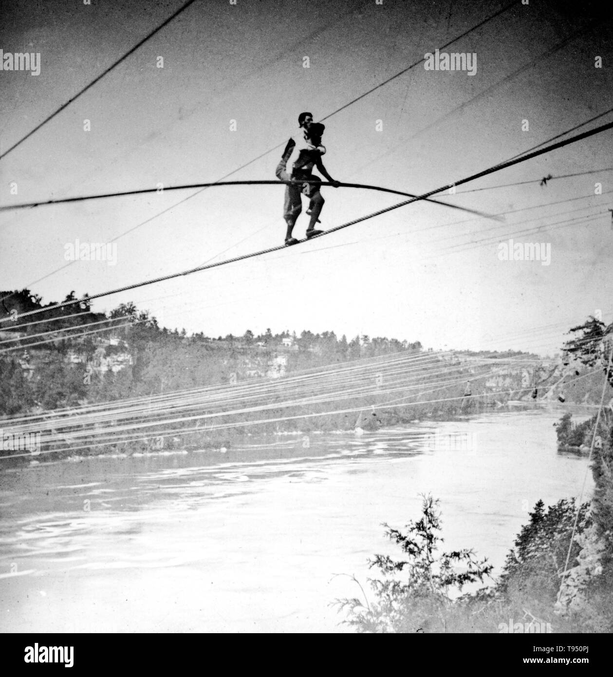 Entitled: 'Blondin carries manager Harry Colcord on back over Niagara Falls.' Charles Blondin (born Jean François Gravelet, February 28, 1824 - February 22, 1897) was a French tightrope walker and acrobat, called the 'Chevalier Blondin', or simply 'The Great Blondin'. At the age of five he was sent to the École de Gymnase at Lyon and, after six months training as an acrobat, made his first public appearance as 'The Boy Wonder'. Stock Photo