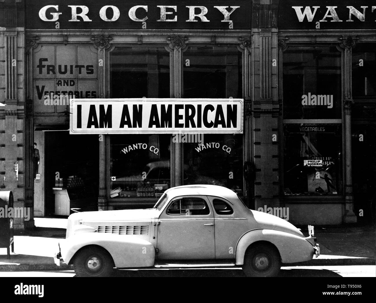 Entitled: 'A large sign reading 'I am an American' placed in the window of a store, at 13th and Franklin streets, on December 8, the day after Pearl Harbor. The store was closed following orders to persons of Japanese descent to evacuate from certain West Coast areas. The owner, a University of California graduate, will be housed with hundreds of evacuees in War Relocation Authority centers for the duration of the war. Stock Photo