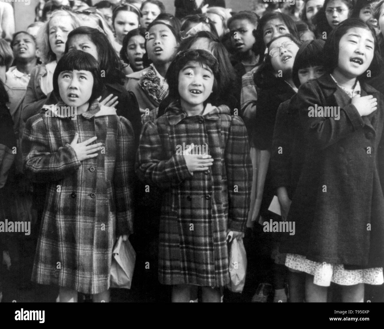 Entitled: 'First graders, some of Japanese ancestry, at the Weill public school pledging allegiance to the United States flag. The evacuees of Japanese ancestry will be housed in War relocation authority centers for the duration of the war.' The Pledge of Allegiance is a solemn vow of loyalty and support for the country. 'I pledge allegiance to the flag of the United States of America, and to the republic for which it stands, one nation under God, indivisible, with liberty and justice for all. Stock Photo