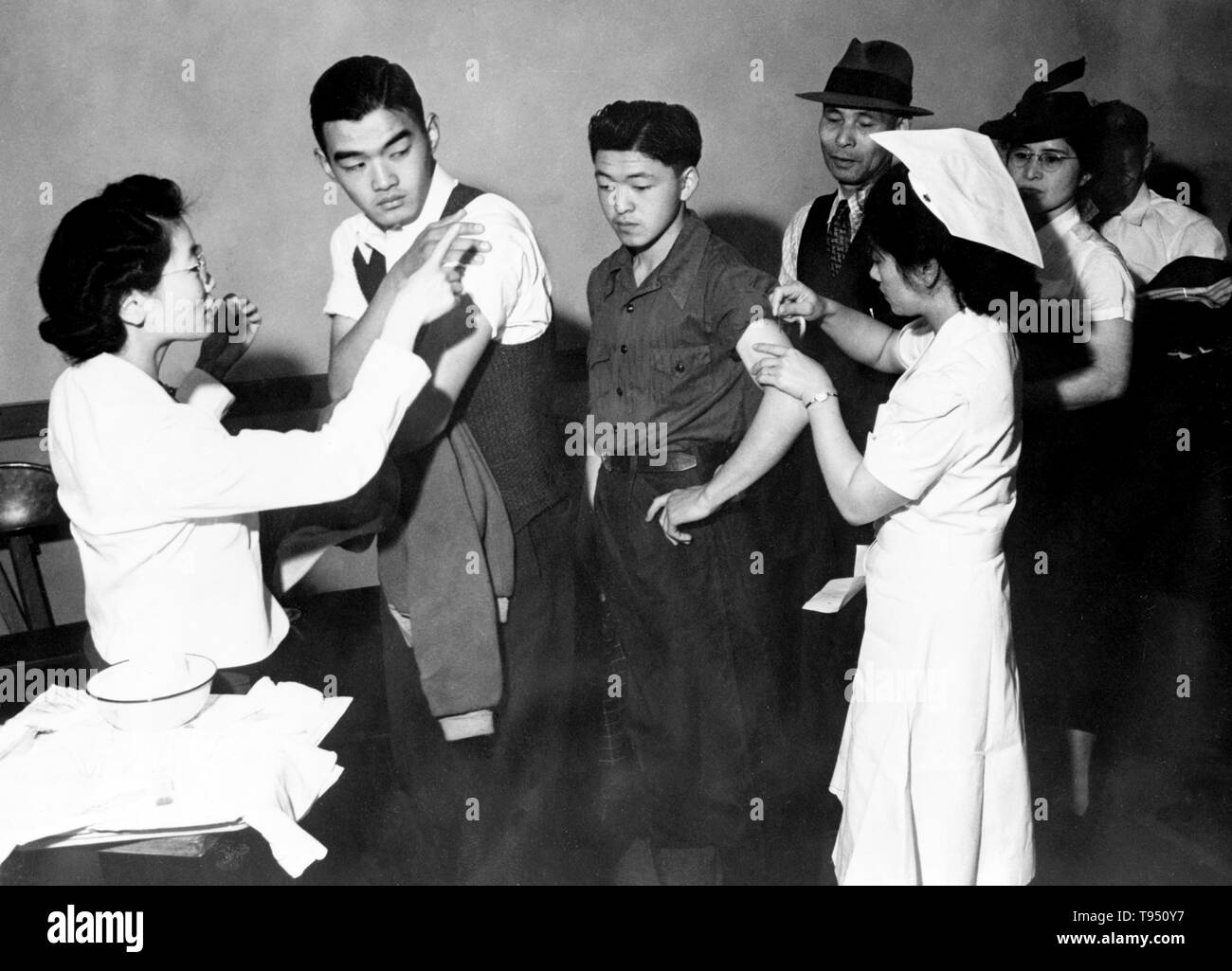Entitled: 'Evacuees of Japanese descent being inoculated as they register for evacuation.' The internment of Japanese-Americans during WWII was the forced relocation and incarceration in camps of 110,000-120,000 people of Japanese ancestry (62% of the internees were US citizens) ordered by President Roosevelt shortly after Japan's attack on Pearl Harbor. Japanese-Americans were incarcerated based on local population concentrations and regional politics. Stock Photo
