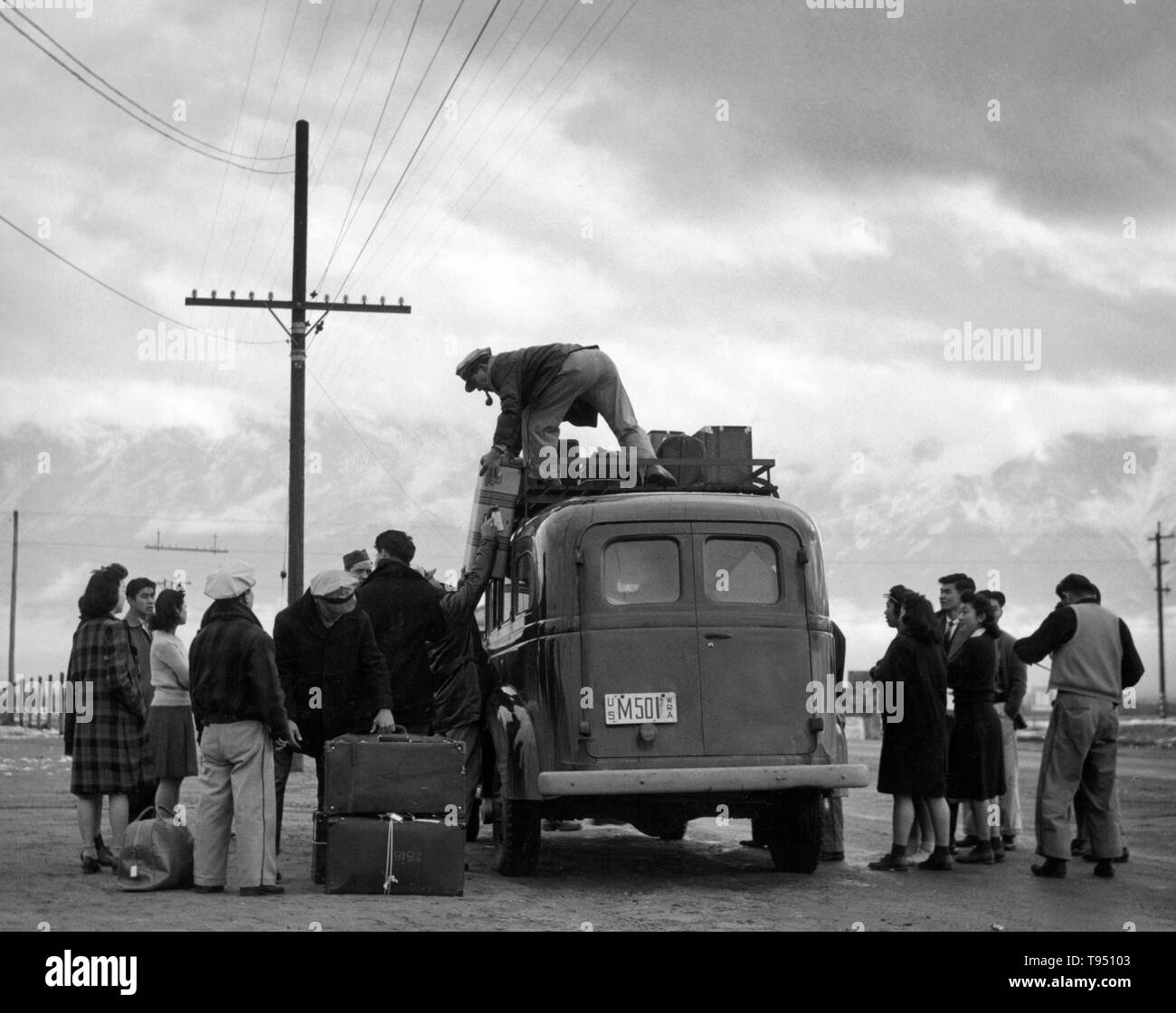 Entitled: 'Loading bus, leaving Manzanar for relocation, Manzanar Relocation Center.' The internment of Japanese-Americans during WWII was the forced relocation and incarceration in camps of 110,000-120,000 people of Japanese ancestry (62% of the internees were US citizens) ordered by President Roosevelt shortly after Japan's attack on Pearl Harbor. Japanese-Americans were incarcerated based on local population concentrations and regional politics. Stock Photo