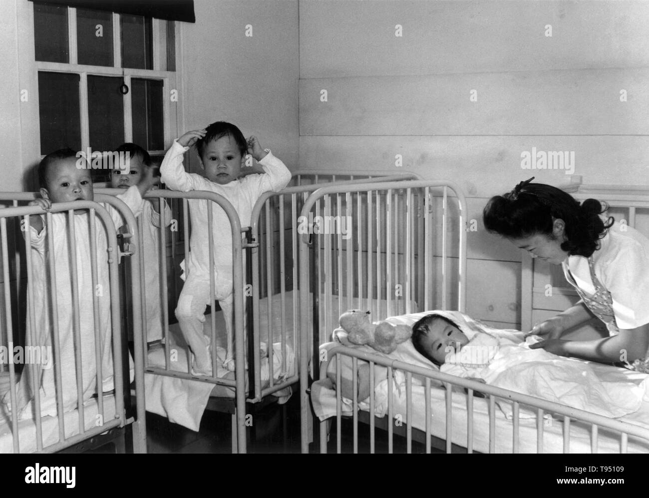Entitled: 'Nursery, orphan infants, Manzanar Relocation Center, California.' The internment of Japanese-Americans during WWII was the forced relocation and incarceration in camps of 110,000-120,000 people of Japanese ancestry (62% of the internees were US citizens) ordered by President Roosevelt shortly after Japan's attack on Pearl Harbor. Japanese-Americans were incarcerated based on local population concentrations and regional politics. Stock Photo