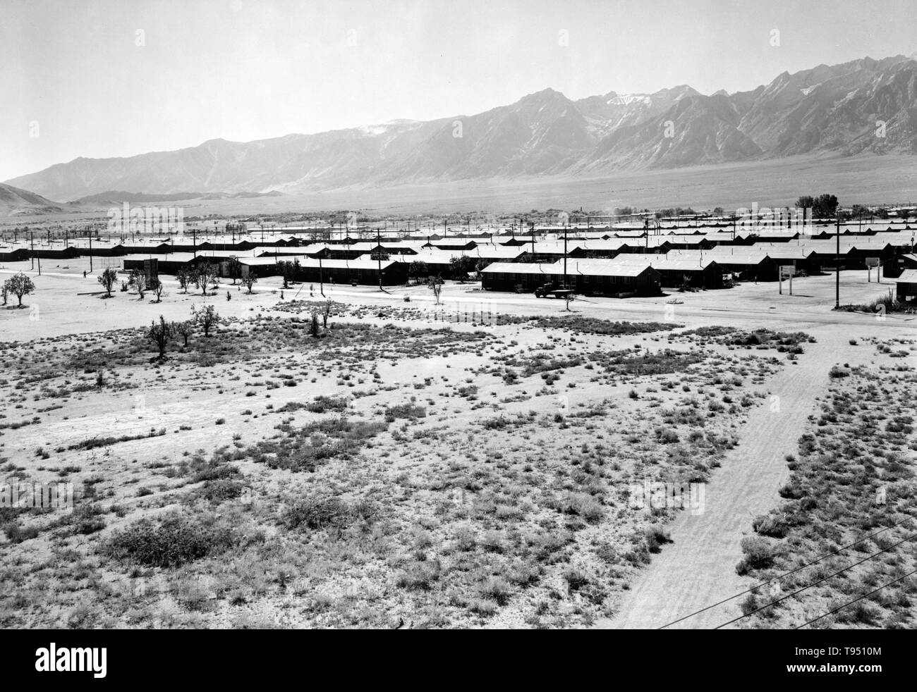 Entitled: 'Manzanar from guard tower, summer heat, view SW, Manzanar Relocation Center.' The internment of Japanese-Americans during WWII was the forced relocation and incarceration in camps of 110,000-120,000 people of Japanese ancestry (62% of the internees were US citizens) ordered by President Roosevelt shortly after Japan's attack on Pearl Harbor. Japanese-Americans were incarcerated based on local population concentrations and regional politics. Stock Photo