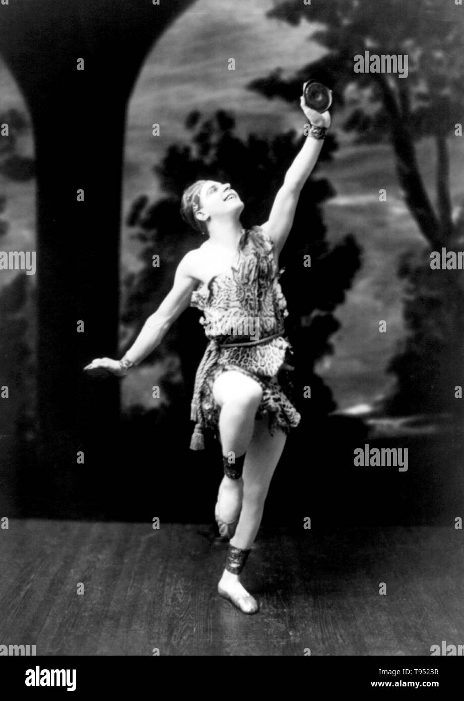 Stafford Pemberton wearing caveman costume and holding disc, in modern dance pose. Modern dance is a broad genre of western concert or theatrical dance, primarily arising out of Germany and the United States in the late 19th and early 20th centuries. No photographer credited, April 13, 1915. Stock Photo