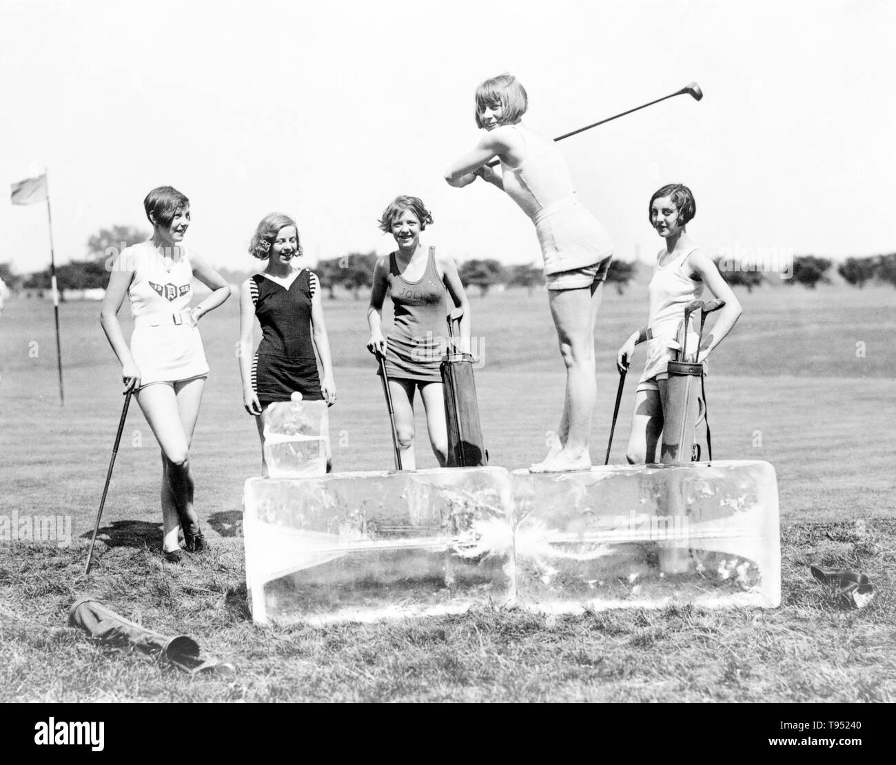 Entitled: 'Icing off at the tee' shows Miss Dorothy Kelly teeing off on a cake of ice. The others in the group are Misses Virginia Hunter, Elaine Griggs, Hazel Brown, and Mary Kaminsky, Washington, D.C. area. Golf is a club and ball sport in which players use various clubs to hit balls into a series of holes on a course in as few strokes as possible. National Photo Company, 1920s. Stock Photo