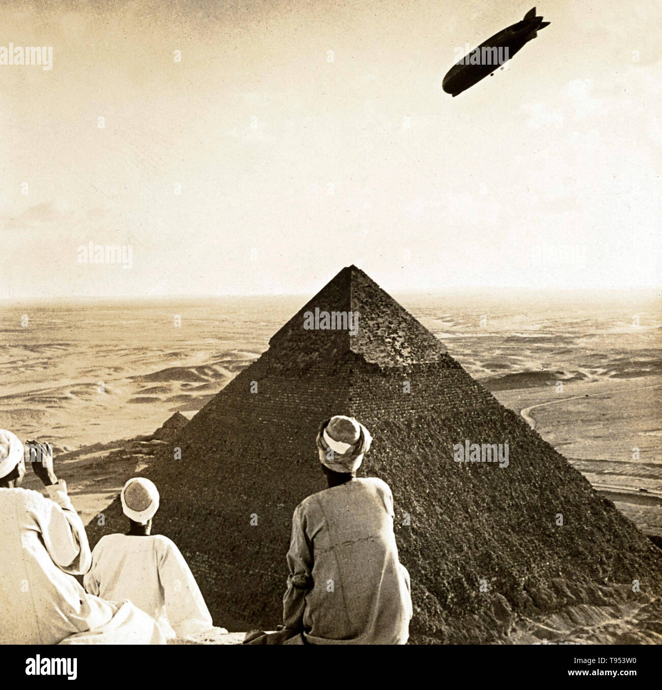 Croppedstereograph of the Graf Zeppelin over the Giza pyramids in Egypt, on April 10, 1931. The LZ 127 Graf Zeppelin was a German-built and -operated, passenger-carrying, hydrogen-filled, rigid airship which operated commercially from 1928 to 1937. When it entered commercial service in 1928, it became the first commercial passenger transatlantic flight service in the world. Stock Photo