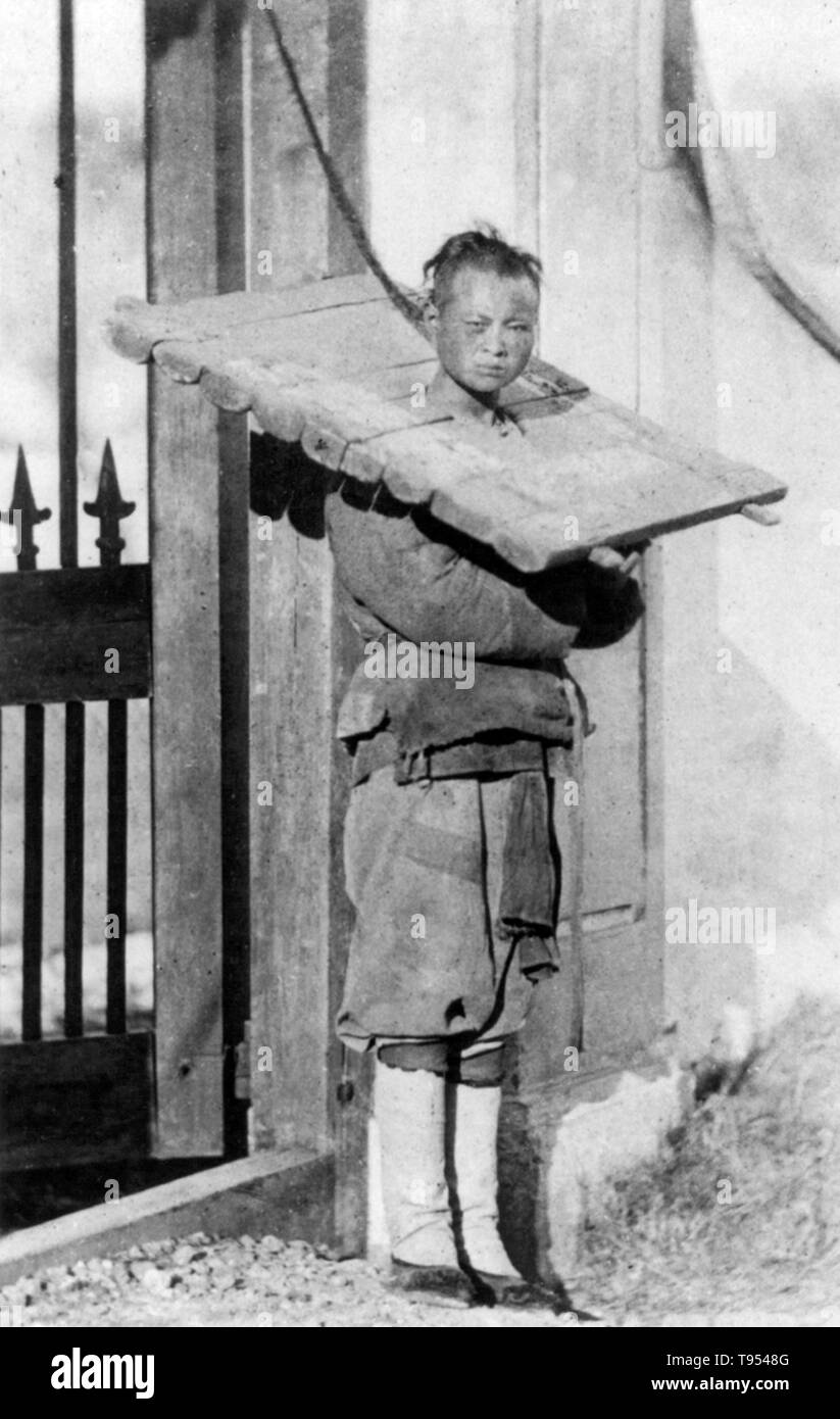 A cangue is a device that was used for public humiliation and corporal punishment in China and some other parts of East Asia and Southeast Asia until the early years of the 20th century. A typical cangue would consist of a large, heavy flat board with a hole in the center large enough for a person's neck. The board consisted of two pieces. These pieces were closed around a prisoner's neck, and then fastened shut along the edges by locks or hinges. Stock Photo