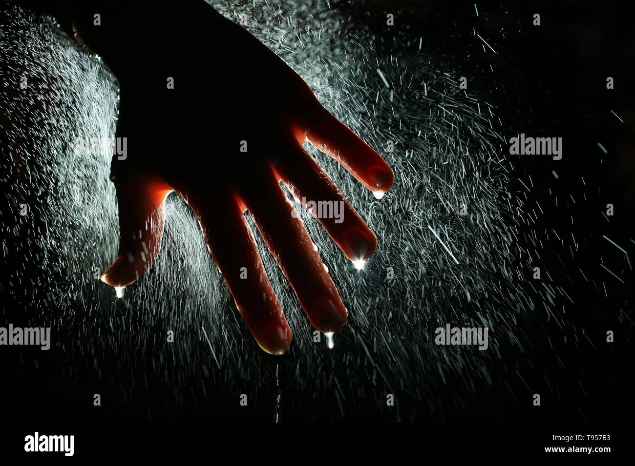 Healing Hand, backlit hand with spread fingers with water mist spray. Stock Photo
