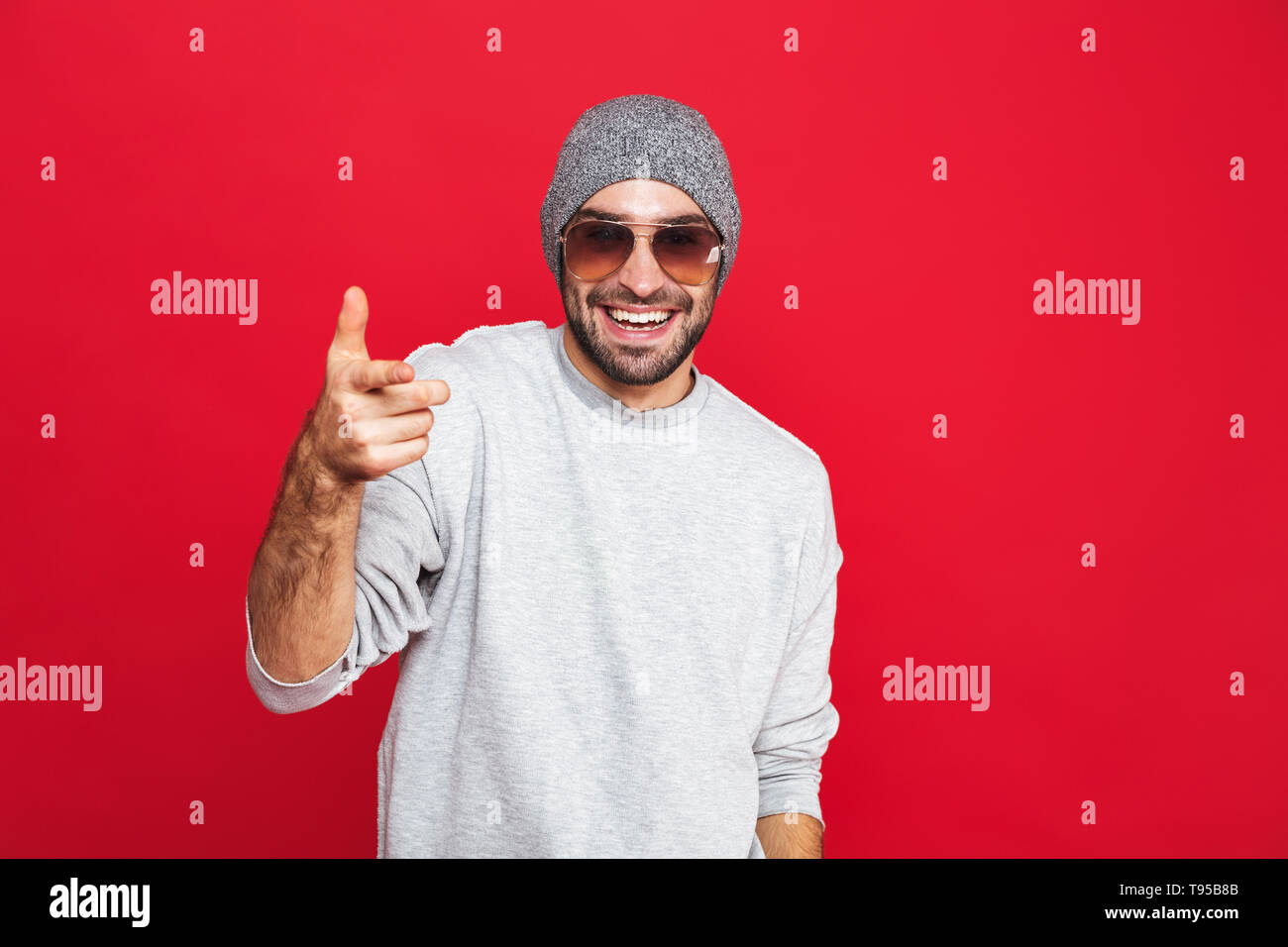 Image of attractive man 30s in sunglasses laughing and pointing finger ...