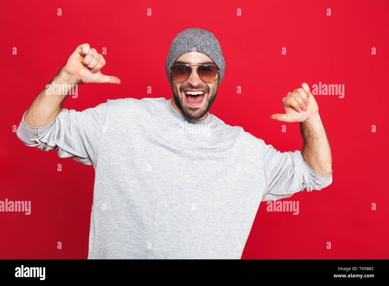 Image of positive man 30s in sunglasses laughing and pointing fingers ...